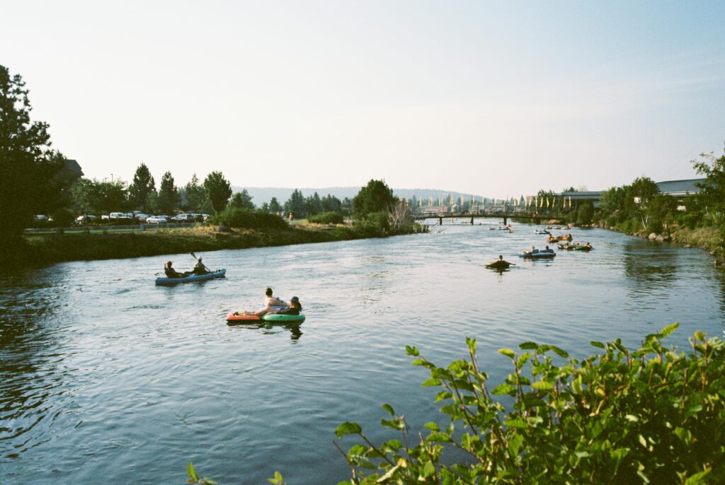 People enjoying a sunny day kayaking on the scenic Deschutes River in Bend, Oregon.